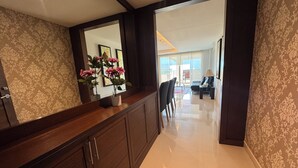A hallway with a wooden cabinet, a mirror, and a potted plant. - Jomtien Beach Penthouses (Pattaya)