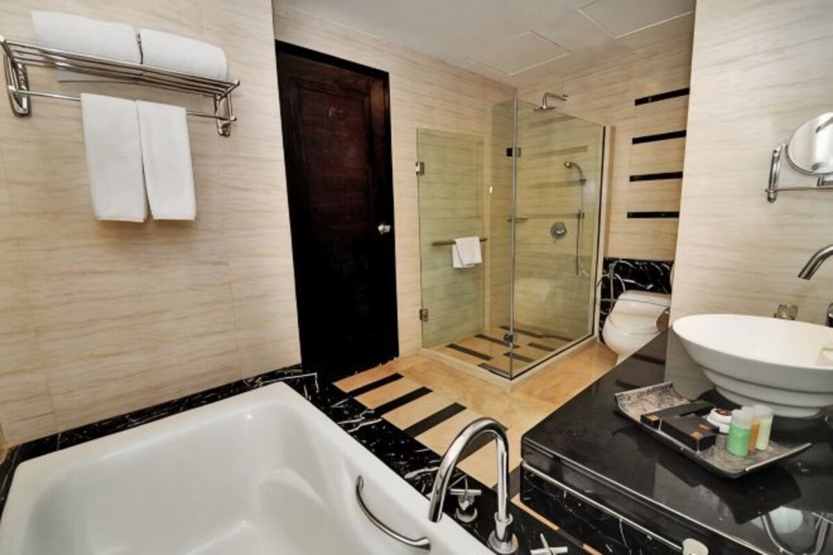 A modern bathroom with a bathtub, shower, and sink.