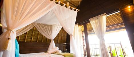 A room with a bed under a canopy, wooden walls, a ceiling fan, and large windows.