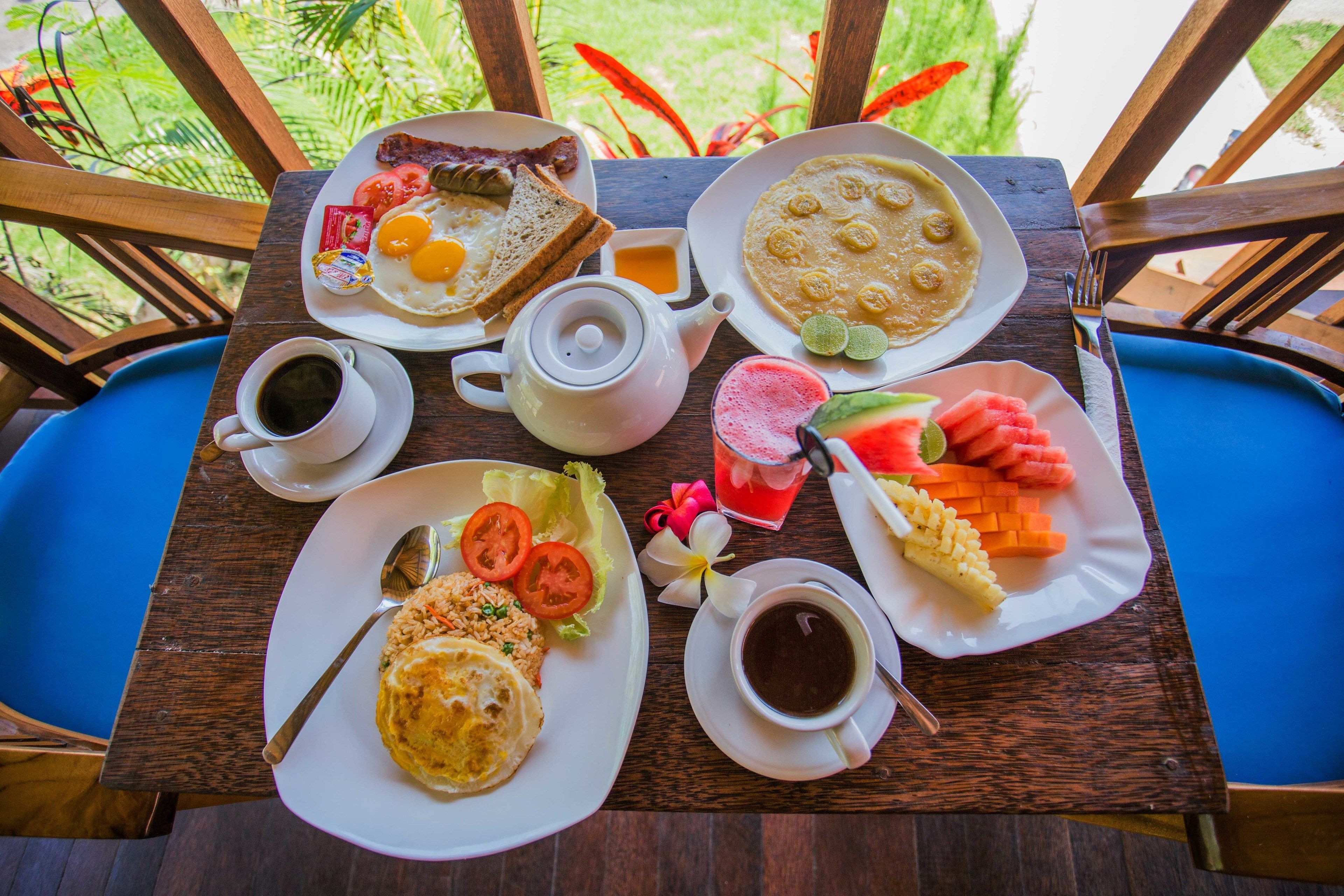 A wooden table with breakfast items including toast, eggs, pancakes, and fruit.