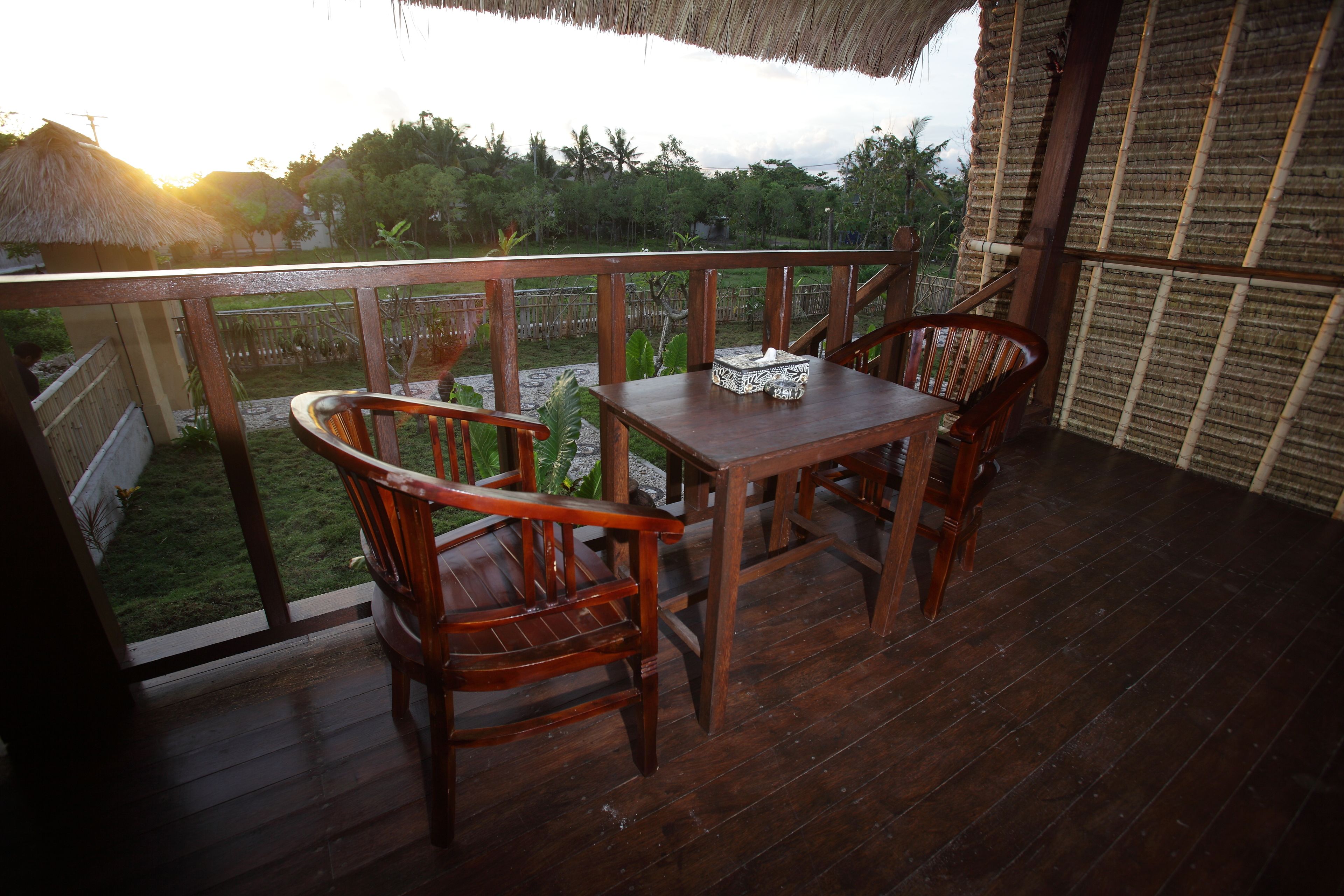 A wooden deck with a table and chairs, overlooking a garden.