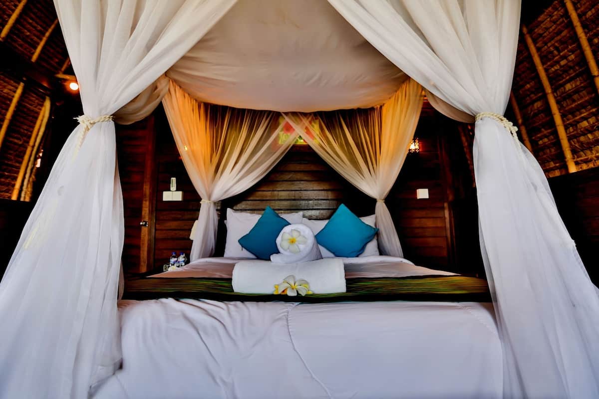 A bed with a canopy, pillows, and a towel.