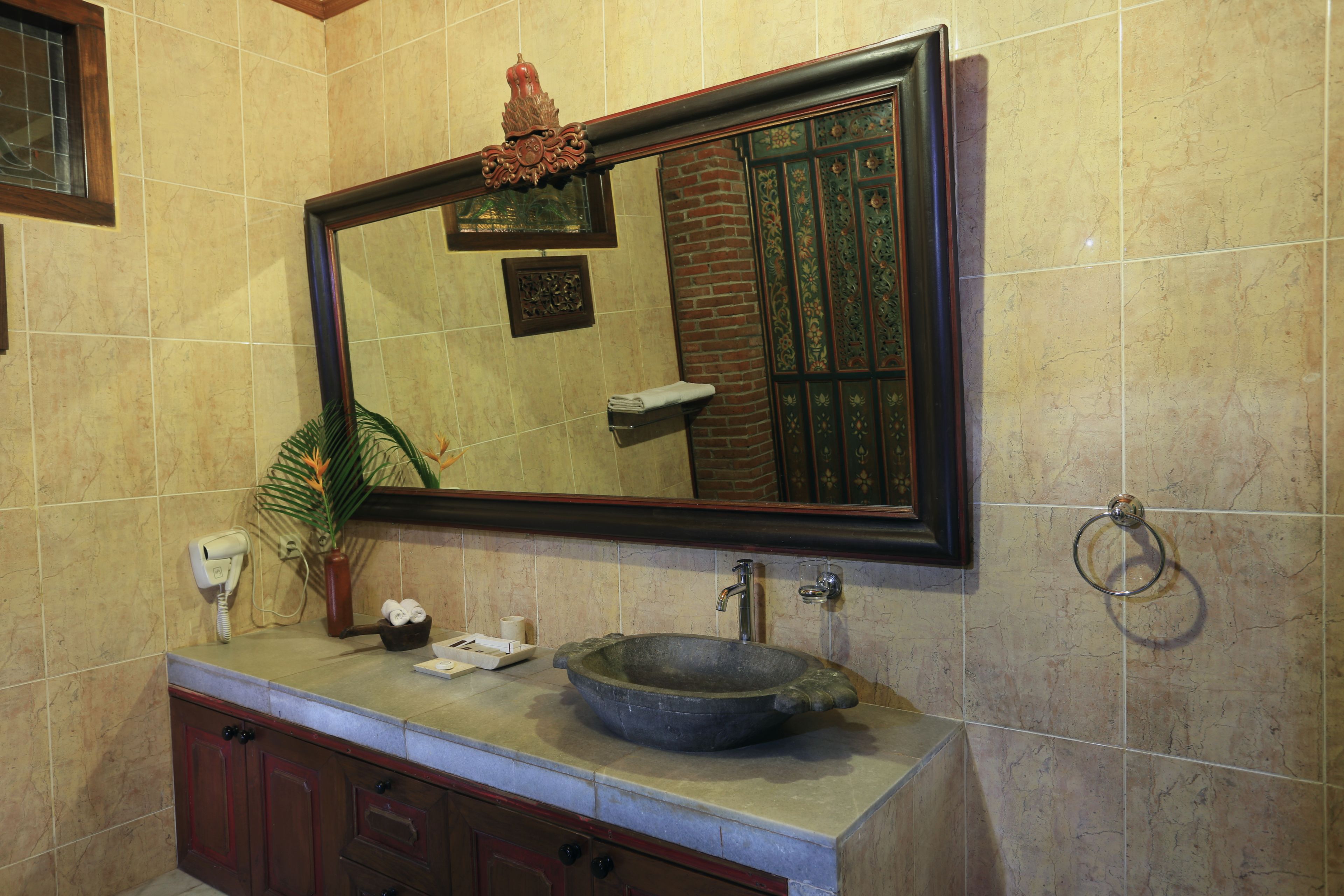 Un baño con un espejo grande, un lavabo de piedra y un aro para toallas.