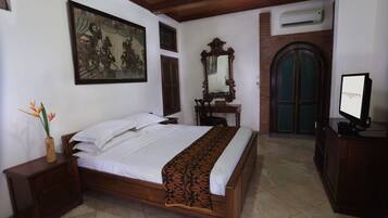 A bedroom with a bed, a nightstand, a dresser, a mirror, and a television.