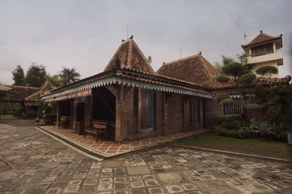 A traditional building with a tiled roof and a small porch area with benches. - Melva Balemong (Ungaran)