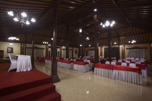A spacious hall with tiered seating, a stage, and multiple chandeliers.