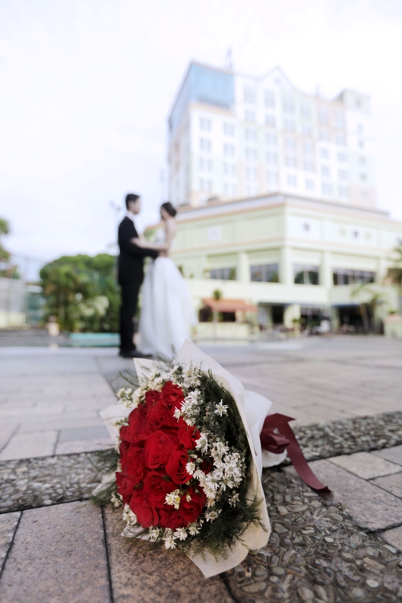 A wedding scene with a bouquet on the ground and a building in the background.