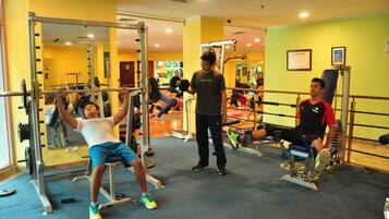 Work out in style with a fully equipped gym featuring a mirrored wall, weightlifting stations, and a bench press area.