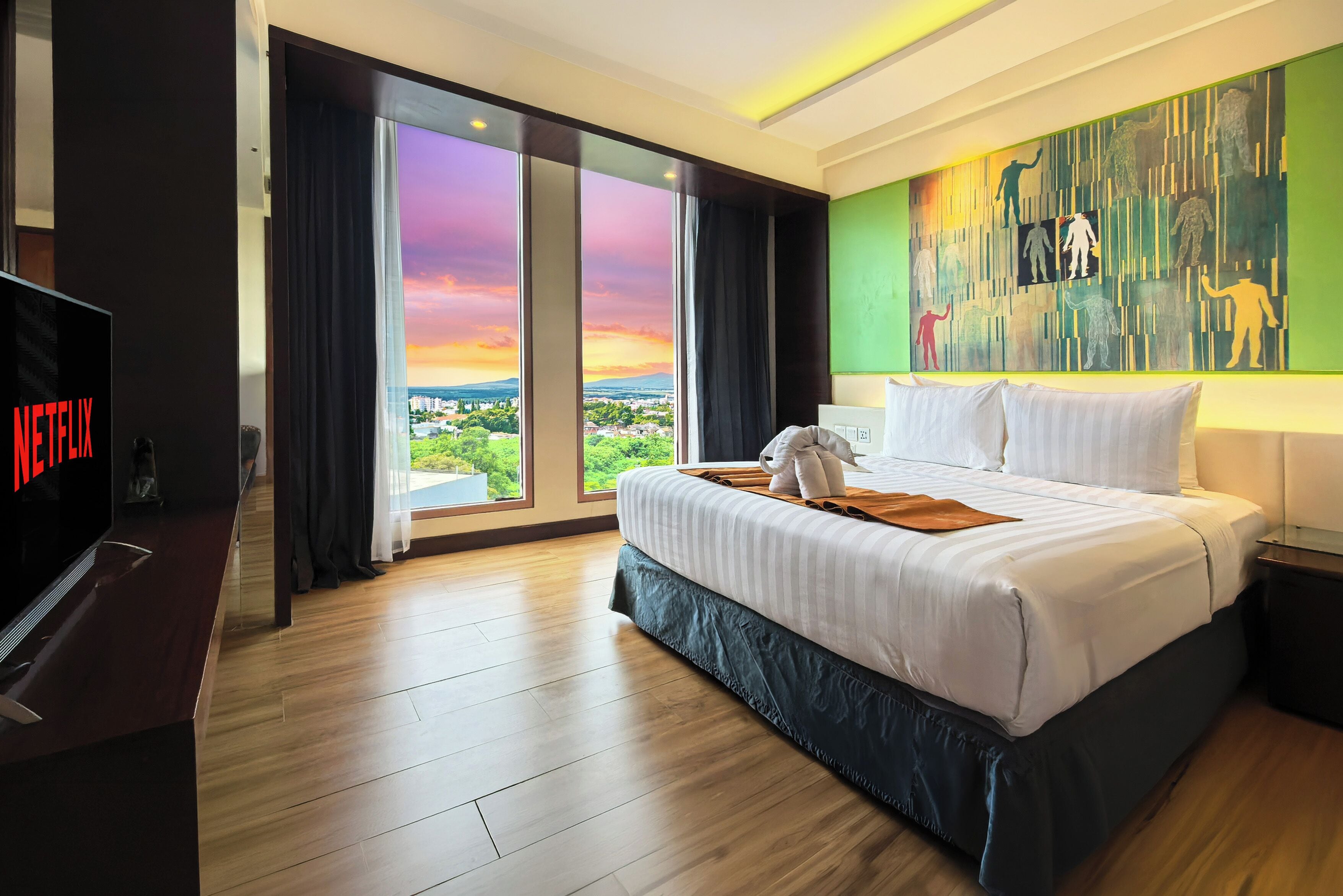 Una habitación de hotel con una cama grande, televisión y vistas a la ciudad.