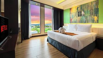 Una habitación de hotel con una cama grande, televisión y vistas a la ciudad.