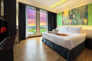 Una habitación de hotel con una cama grande, televisión y vistas a la ciudad.