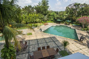 Una piscina al aire libre, sombrillas, sillones reclinables de piscina