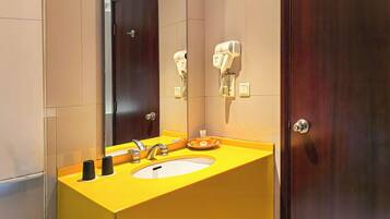 Un baño con un lavabo amarillo, un espejo, un secador de pelo y una puerta.