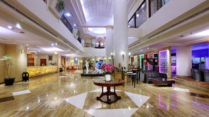 A spacious lobby with a reception desk, a central decorative fountain, and a seating area with a coffee table. - Grand Candi Hotel (Semarang)