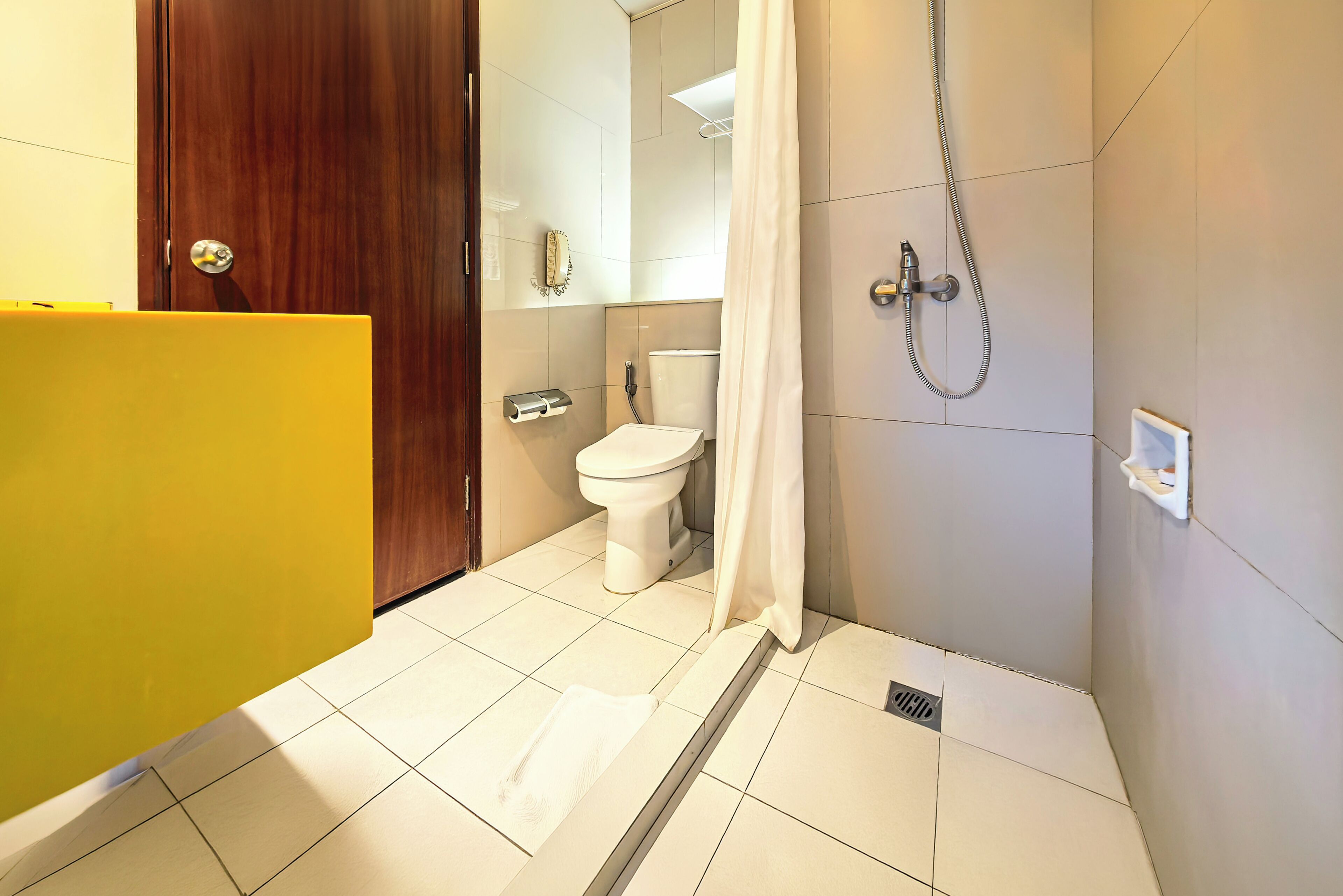 Un baño con inodoro, ducha y un lavabo amarillo.