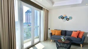 A modern living room with a grey sofa, orange cushions, a round coffee table, and a decorative wall piece. - @HOM Simpang Lima Semarang (Semarang)