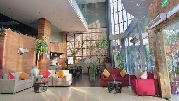 A modern lobby with seating areas, a reception desk, and a large glass wall with natural light. - @HOM Simpang Lima Semarang (Semarang)