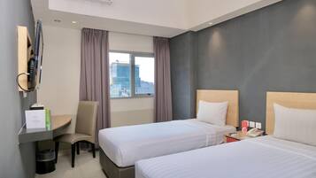 A hotel room with two beds, a desk, a chair, a telephone, and a window with curtains.
