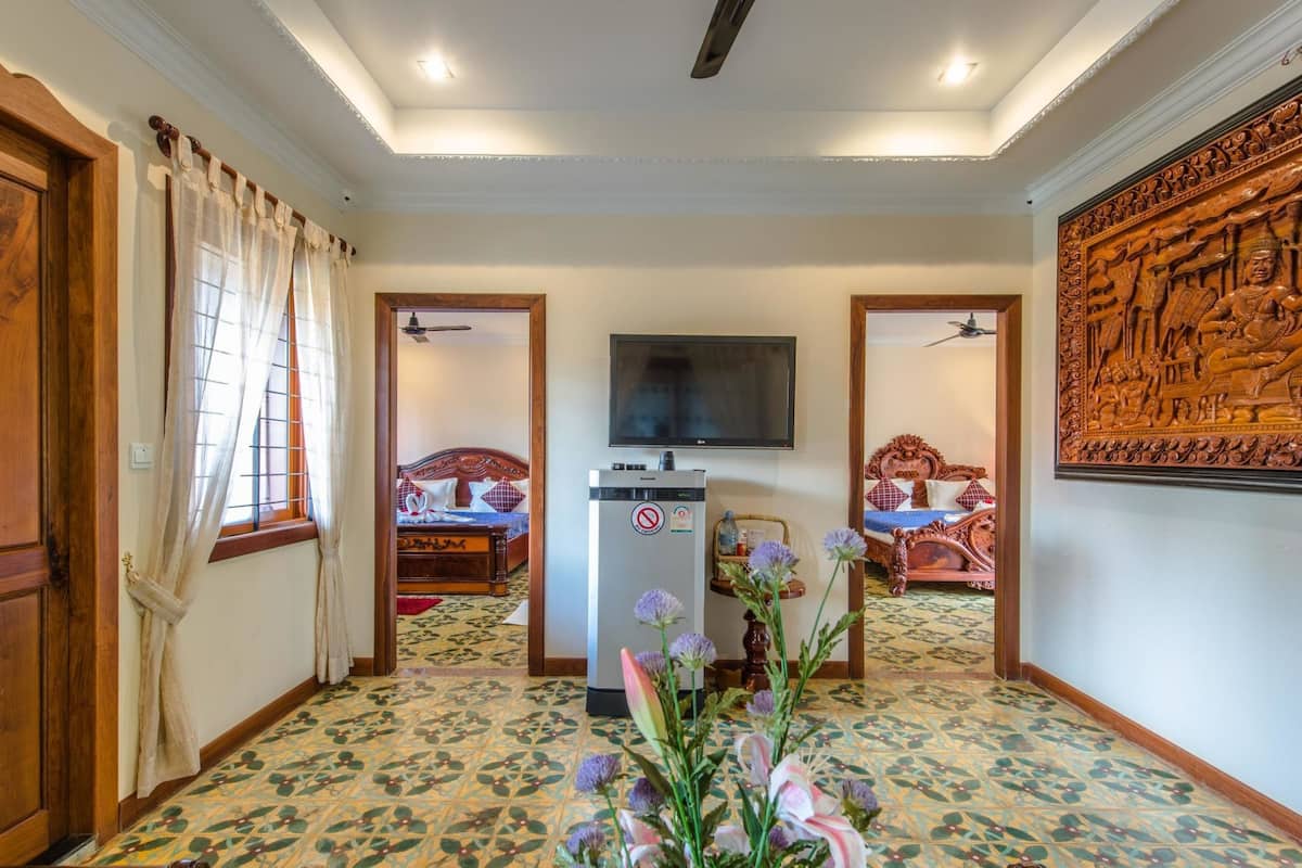 Habitación de hotel con una cama grande, televisión, refrigerador y un elemento decorativo en la pared.