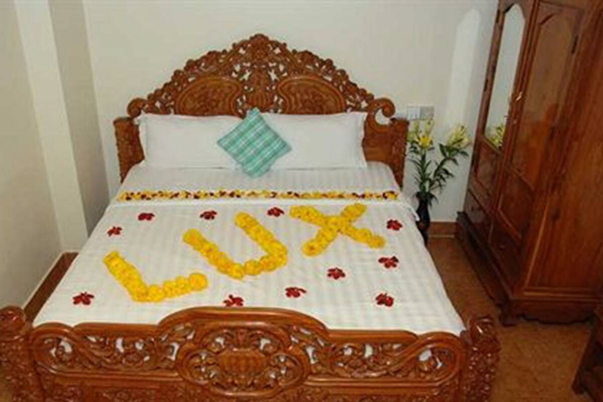 Una cama de madera con colcha blanca y almohada decorativa.