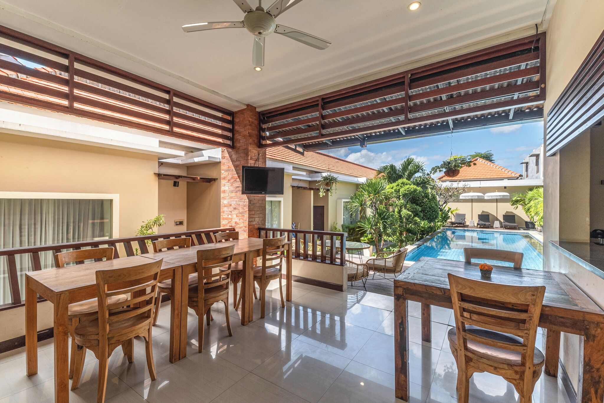 A spacious indoor area with a pool, wooden furniture, and a ceiling fan.