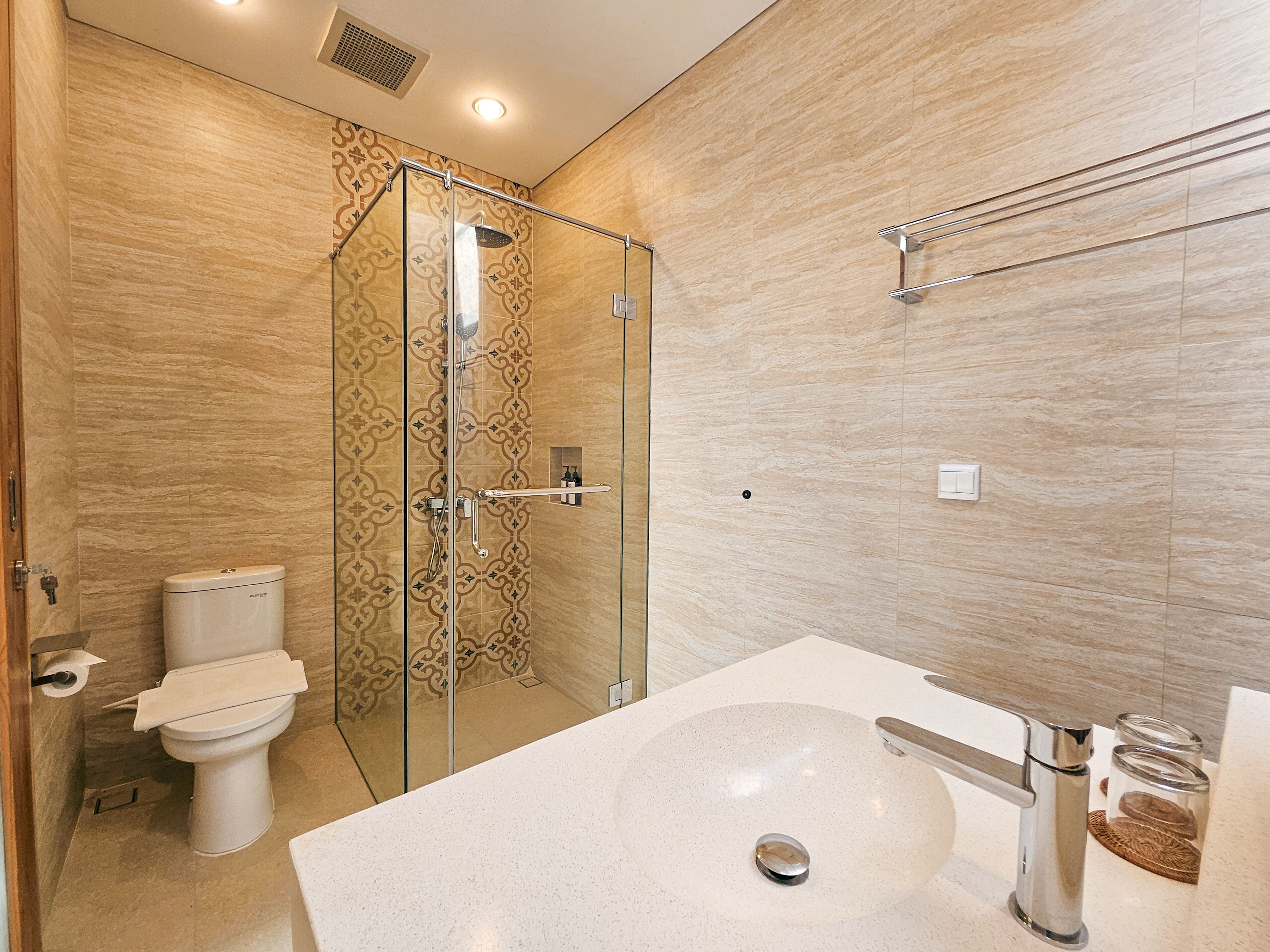 A modern bathroom with a glass-enclosed shower, a white sink, and a toilet.