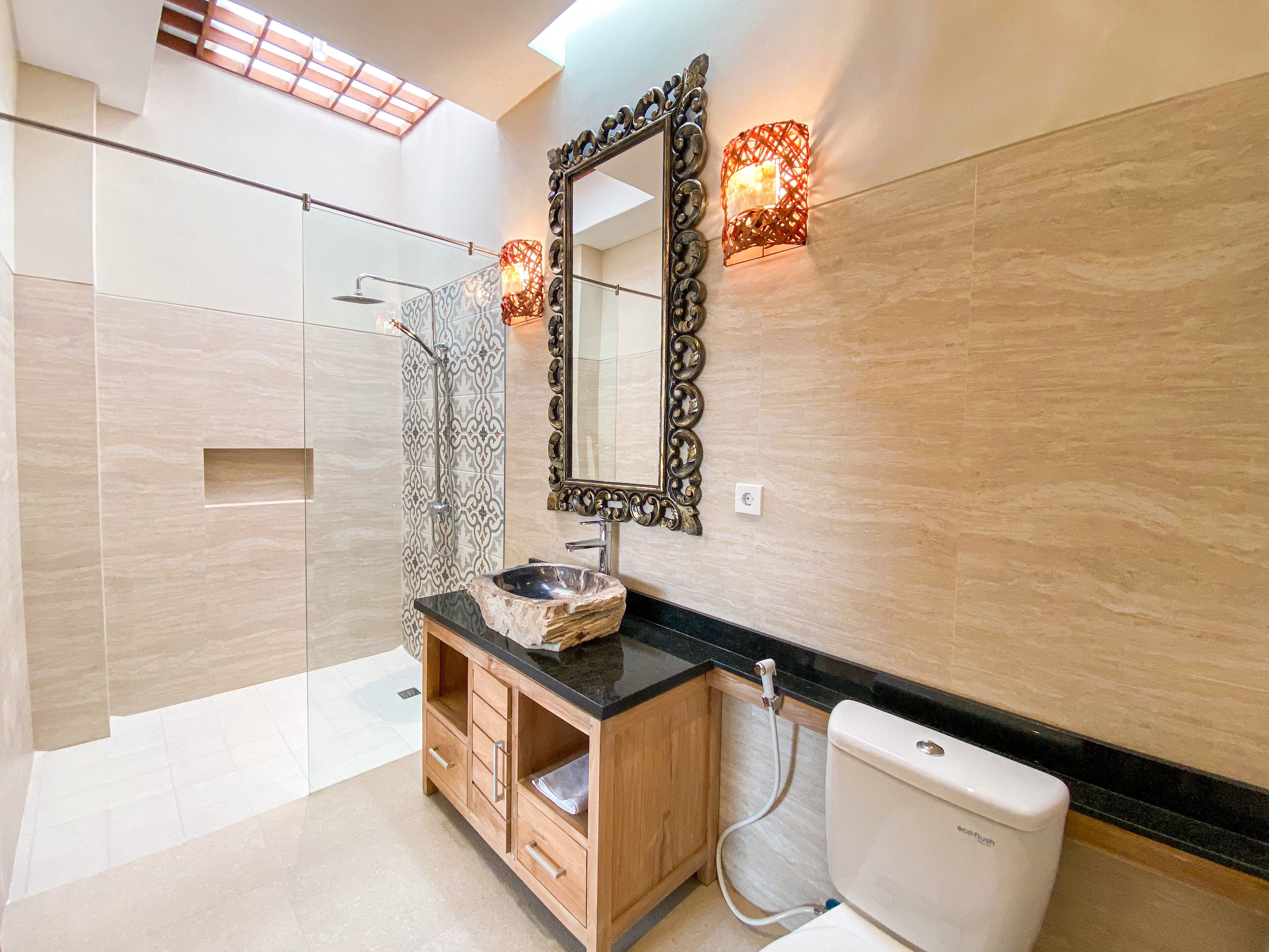 Un bagno moderno con uno specchio grande, un lavabo con piano in marmo, mobili contenitori in legno e un water.