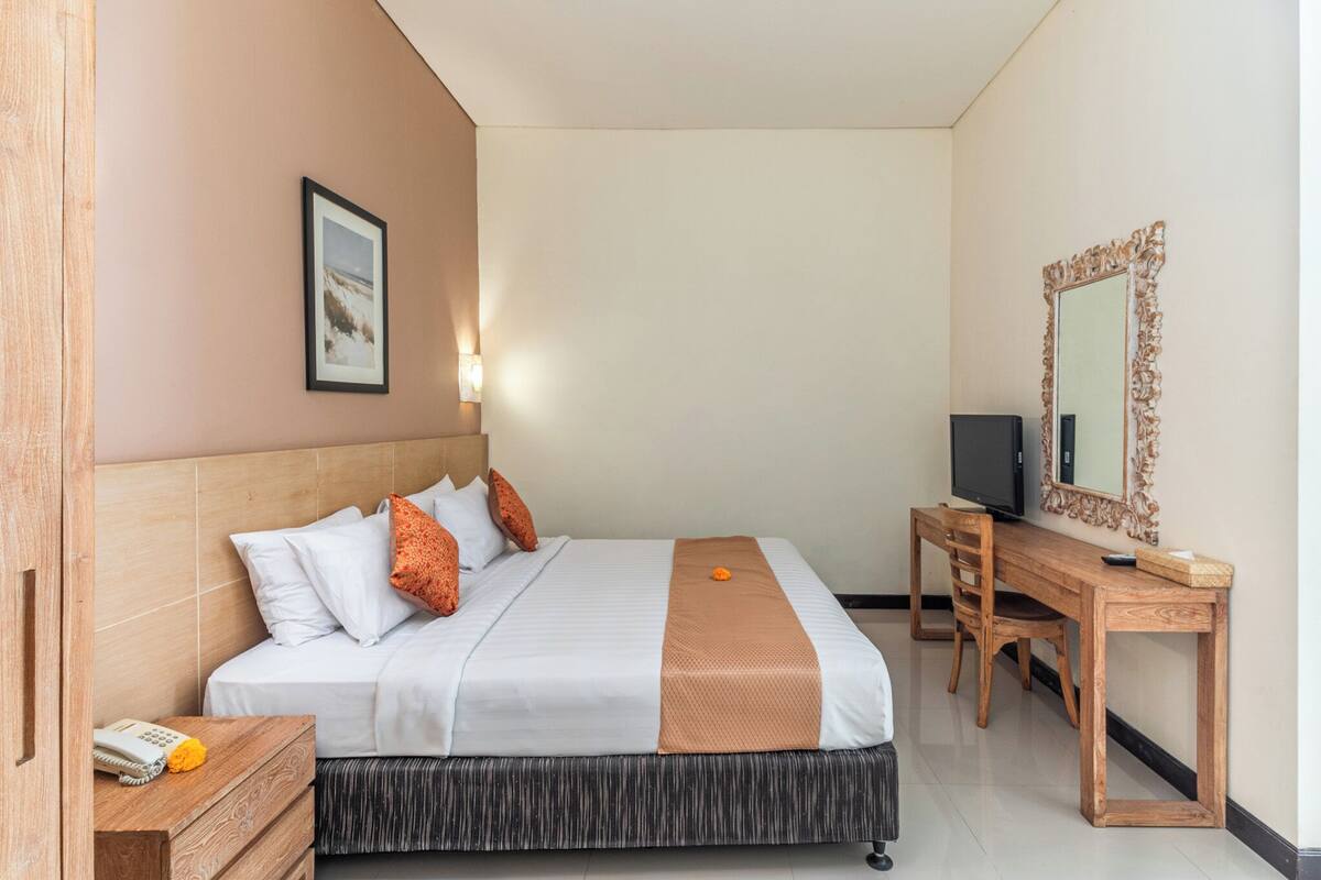 A hotel room with a bed, a desk, a television, and a mirror.