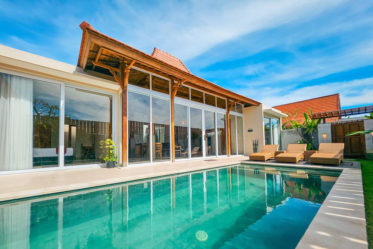 A modern house with a swimming pool, large sliding glass doors, and outdoor seating.