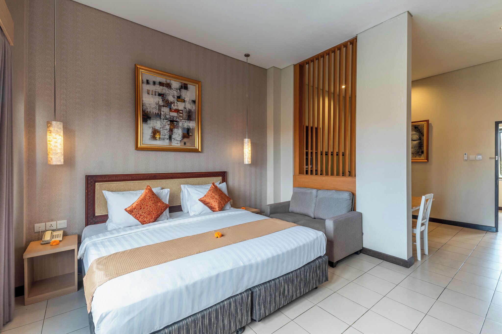 A hotel room with a large bed, a bedside table with a phone, a chair, and a small table.