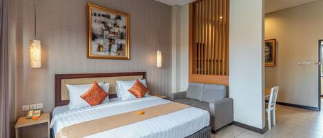 A hotel room with a large bed, a bedside table with a phone, a chair, and a small table.
