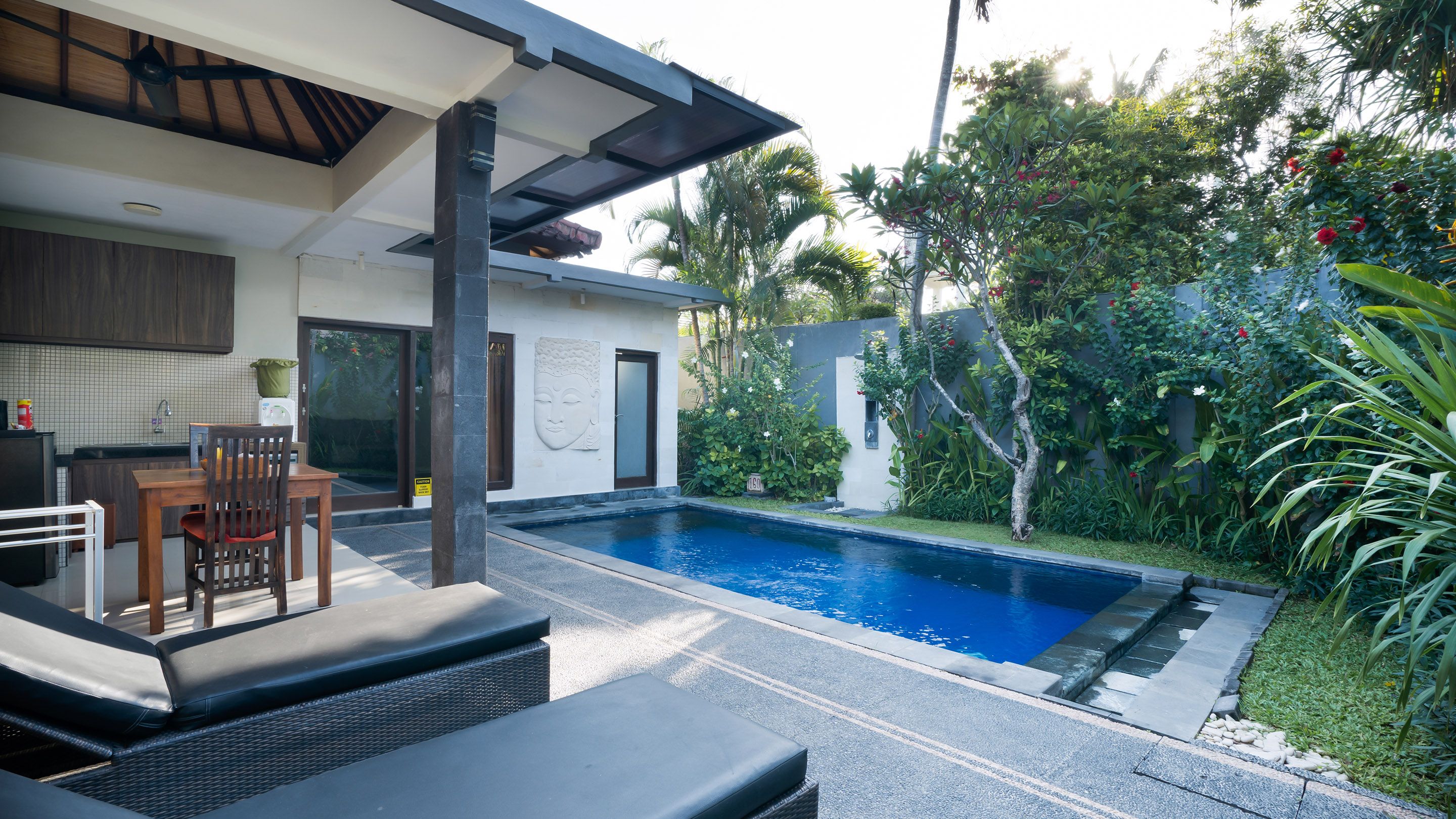 Un espace piscine extérieur moderne, aménagé avec un ensemble de mobilier de jardin et une petite table.