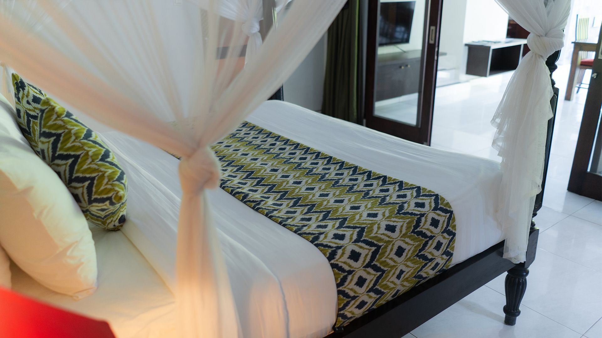 A bed with a patterned bedspread, a canopy, and pillows with geometric designs.