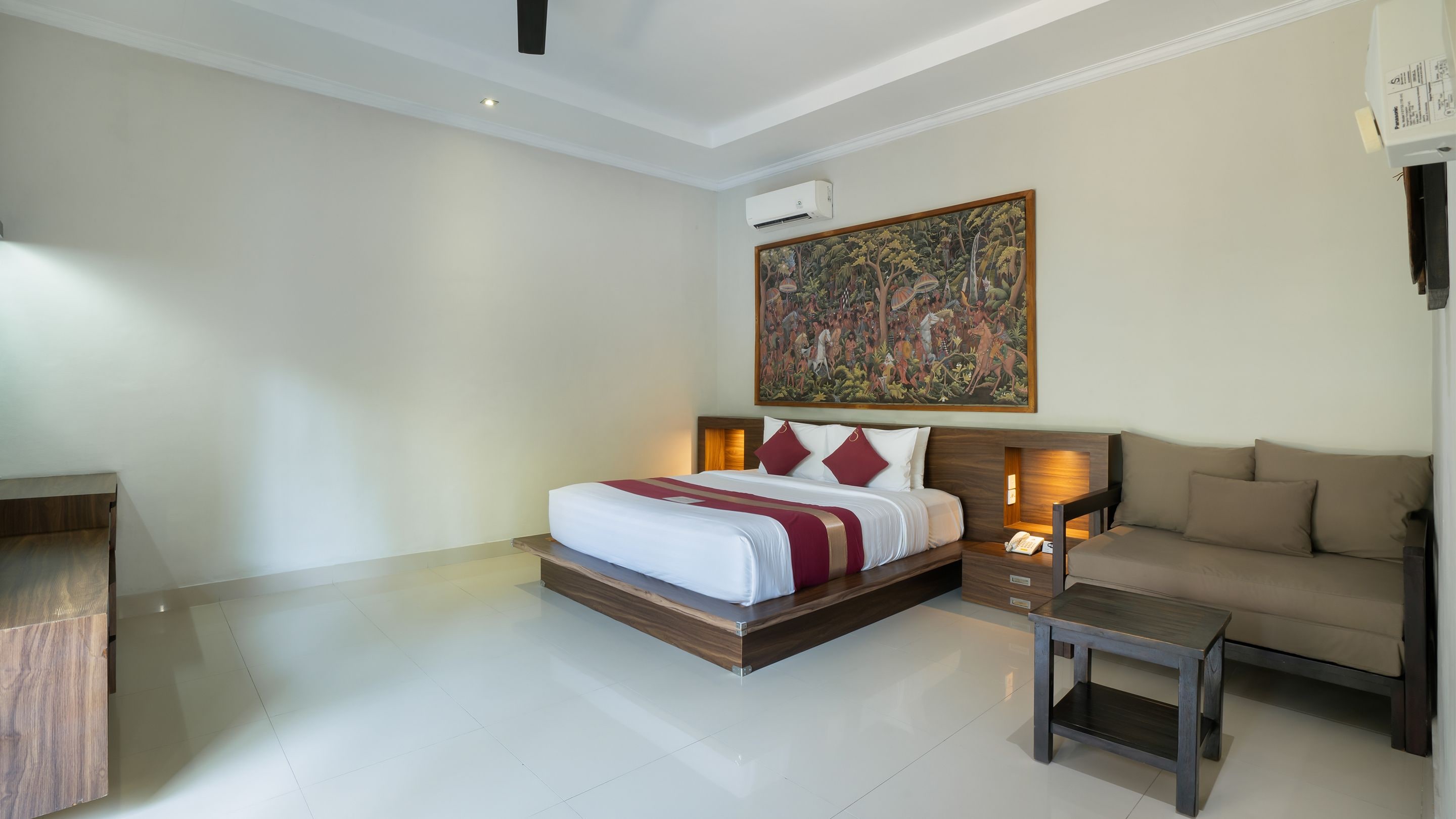 Een hotelkamer met een bed, een bank, een eettafeltje en een schilderij aan de muur.