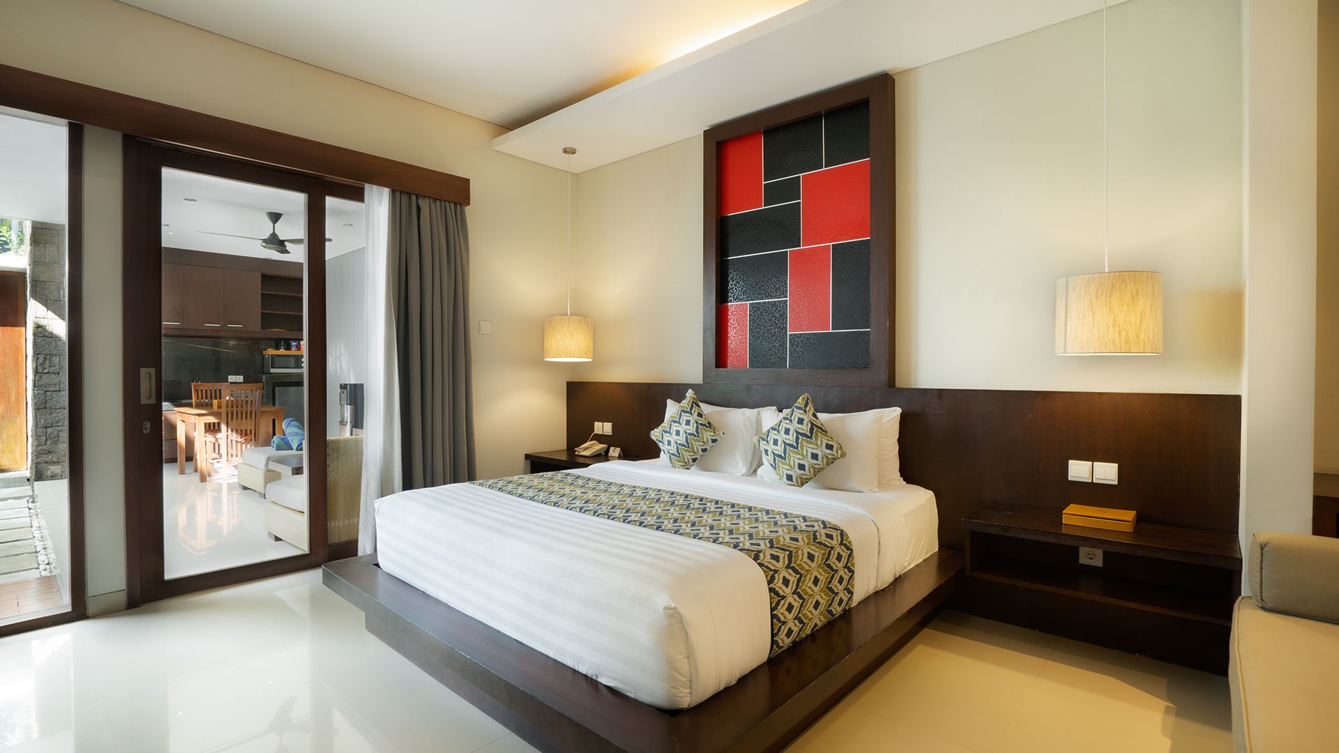 Una habitación de hotel moderna con una cama grande, una zona de comedor y vistas a través de una puerta corredera.