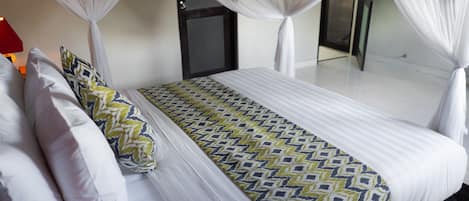 Uma cama com colcha estampada, almofadas brancas e dossel.