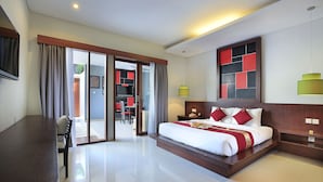 A modern hotel room with a large bed, a desk, and a view of the outdoor area. - Samaja Beachside Villas (Seminyak)