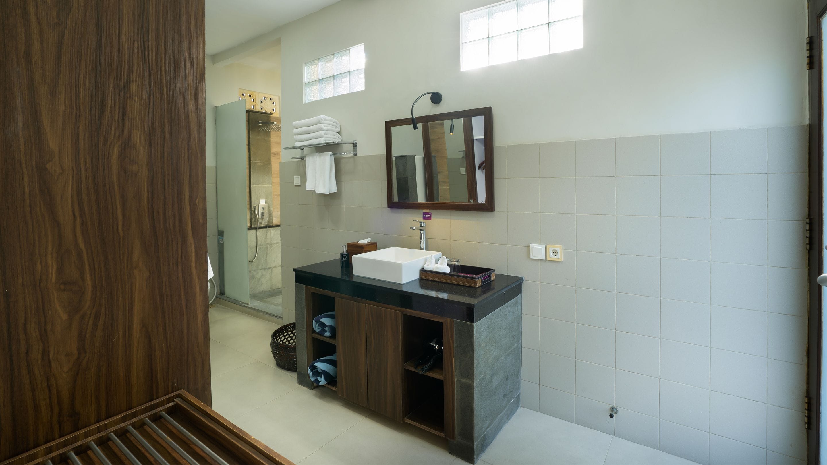 A modern bathroom with a large mirror, a sink, and a shower area.