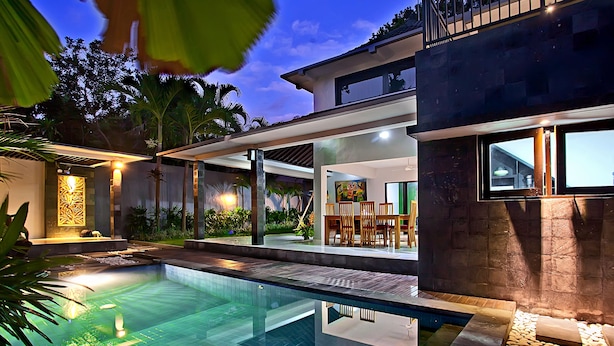 A modern house with a swimming pool, outdoor seating, and a well-lit patio area. - Samaja Beachside Villas (Seminyak)