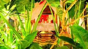 A dining area with a table set for two, surrounded by lush tropical plants. - Residence Wat Damnak (Siem Reap)
