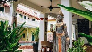 A statue in a covered outdoor area with a pool and potted plants. - Residence Wat Damnak (Siem Reap)