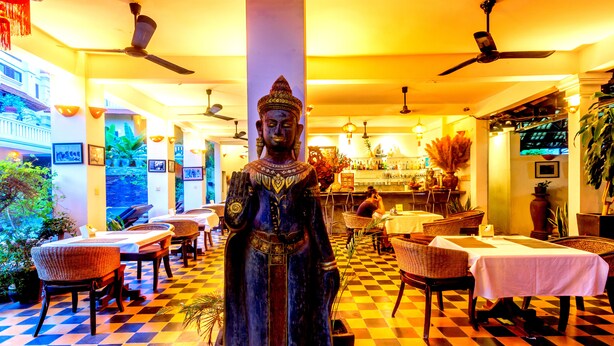 A restaurant with a Buddha statue centerpiece, checkered floor, and indoor plants. - Residence Wat Damnak (Siem Reap)