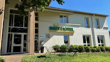 Un bâtiment d'hôtel avec une enseigne indiquant « BRIT HOTEL » et une entrée bien visible avec des portes en verre.