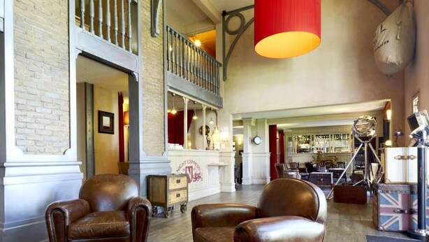 Un vestíbulo amplio con sillones de cuero, una zona de bar y una escalera que conduce a un nivel superior.