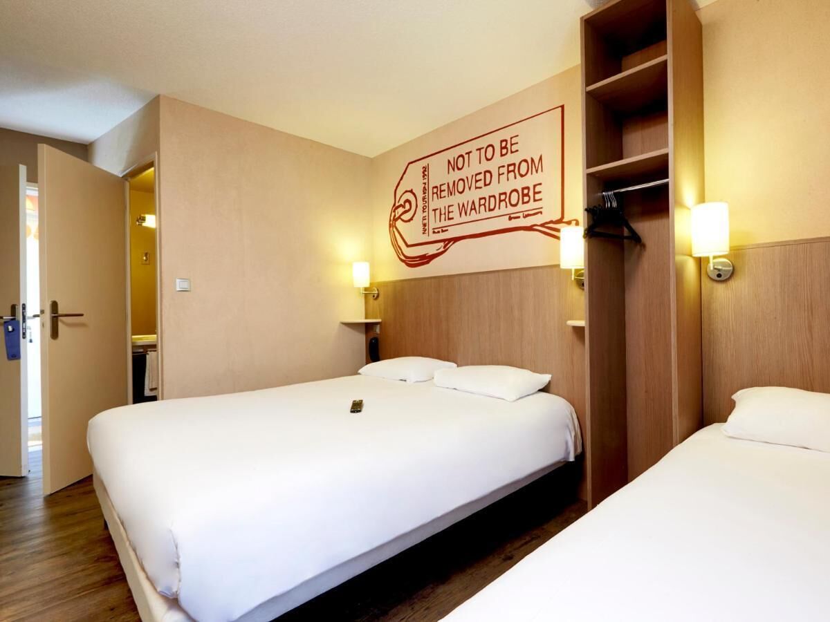 A hotel room with a large bed, a wardrobe, and a wall-mounted sign.