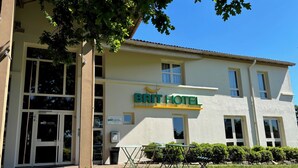 Un hotel con un letrero que dice 'BRIT HOTEL' y una amplia entrada con ventanales.