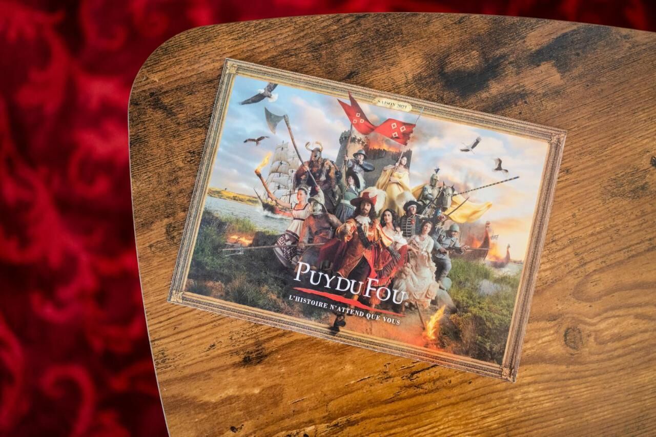 A wooden board with a framed picture of a historical scene titled "PUYDUFOU" and the subtitle "L'histoire n'attend que vous".