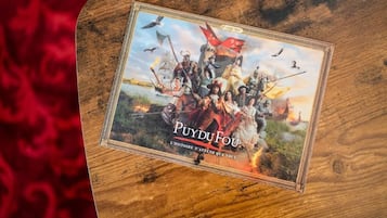 A wooden board with a framed picture of a historical scene titled "PUYDUFOU" and the subtitle "L'histoire n'attend que vous".