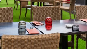 Un área de comedor al aire libre con sillas y mesas de mimbre, sombrillas y un letrero que dice 'RESERVE'.