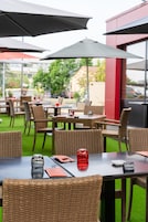 Un espace de restauration en plein air avec des chaises et des tables en osier, des parasols et un panneau indiquant « RESERVÉ ».